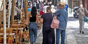 Τρεις πολίτες περπατούν μπροστά από ταβέρνα