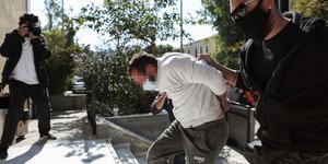 Αστυνομικός οδηγεί συλληφθέντα στα δικαστήρια