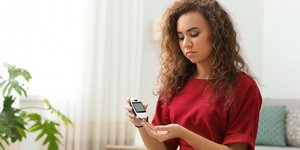 Νεαρή γυναίκα χρησιμοποιεί ψηφιακό γλυκομετρικό στο σπίτι για έλεγχο του διαβήτη