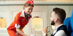 Γυναίκα αεροσυνοδός σερβίρει επιβάτη