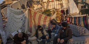 Ανδρες καπνίζουν ανάμεσα σε χαλάσματα σπιτιών