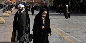 Μια γυναίκα και ένας κληρικός περπατούν στην πόλη Κομ του Ιράν