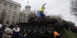 Ανδρας ανεβαίνει πάνω σε άρμα μάχης παρκαρισμένο έξω από την πρεσβεία της Ρωσίας