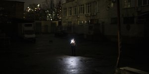 Γυναίκα στο Κίεβο φωτίζει με κινητό τον σκοτεινό δρόμο