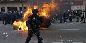 Αστυνομικός περπατά δίπλα από φωτιά σε κάδο