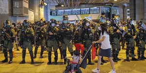 Γυναίκα με καρότσι με παιδί περνά μπροστά από αστυνομικούς στο Χονγκ Κονγκ