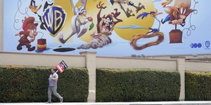 Απεργός μπροστά από graffiti της Warner Bros στο Χόλιγουντ