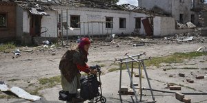 Μια ηλικιωμένη γυναίκα στέκεται δίπλα σε κατεστραμμένα κτίρια στη Ζαπορίζια