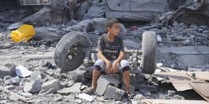 Παιδάκι κάθεται ανάμεσα στα ερείπια που έχουν προκαλέσει οι βομβαρδισμοί στη Γάζα