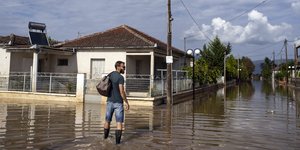 Aνδρας περπατά σε πλημμυρισμένο χωριό στη Θεσσαλία