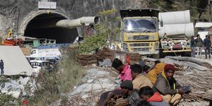 Κόσμος κάθεται κοντά στην τοποθεσία μιας υπό κατασκευή οδικής σήραγγας που κατέρρευσε παγιδεύοντας 41 εργάτες στη Silkyara στη βόρεια ινδική πολιτεία Uttarakhand