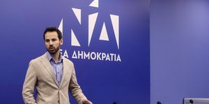 Ο Νίκος Ρωμανός πίσω από καρέκλες σε πάνελ