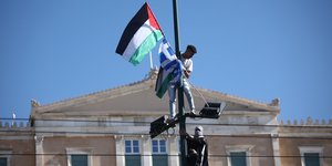 H στιγμή που νεαρός Παλαιστίνιος υψώνει τη σημαία της χώρας του μαζί με την ελληνική σε κολώνα στο Σύνταγμα
