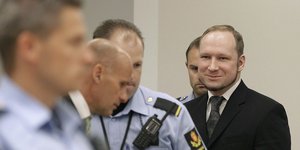 O Αντερς Μπρέιβικ χαμογελά ανάμεσα σε αστυνομικούς