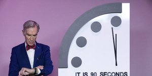 Ο επιστήμονας Νιλ Νάι, κοιτάζει το ρολόι του δίπλα από το Ρολόι της Αποκάλυψης