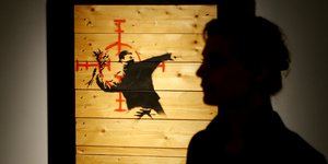Μια γυναίκα στέκεται δίπλα σε ένα έργο τέχνης του Βρετανού καλλιτέχνη Banksy