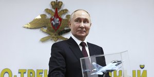 Ο Βλάντιμιρ Πούτιν χαμογελάει κρατώντας μινιατούρα πολεμικού αεροσκάφους