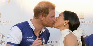 Ο Χάρι και η Μέγκαν ανταλλάσσουν ένα φιλί κρατώντας στα χέρια τους το τρόπαιο του Royal Salute Polo Challenge 