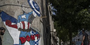 Ένας άνδρας περπατά μπροστά από μια τοιχογραφία που απεικονίζει τον πρόεδρο των ΗΠΑ Τζο Μπάιντεν ως υπερήρωα που υπερασπίζεται το Ισραήλ σε έναν δρόμο στο Τελ Αβίβ