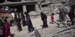 Παλαιστίνιοι περπατούν μέσα στην καταστροφή μετά την ισραηλινή αεροπορική και χερσαία επίθεση στο Χαν Γιουνίς, στη νότια Λωρίδα της Γάζας