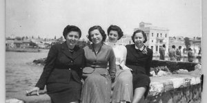 Αίγινα, κομψές κυρίες στον μώλο του Αγίου Νικολάου -Στο βάθος το κτήριο Βογιατζή