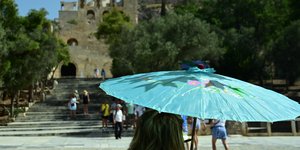 Γυναίκα με ομπρέλα εν μέσω καύσωνα στην Αθήνα