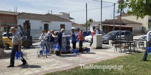 Κάτοικοι περιμένουν για λίγα μπουκάλια πόσιμο νερό
