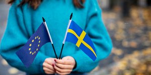 Γυναίκα κρατάει τις σημαίες της Σουηδίας και της ΕΕ