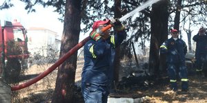 Πυροσβέστες με μάνικα σβήνουν φωτιά