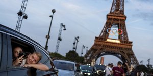 Επιβάτες στο πίσω μέρος ενός ταξί βιντεοσκοπούν τον εαυτό τους καθώς φεύγουν από τον Πύργο του Άιφελ διακοσμημένο με τους Ολυμπιακούς δακτυλίους ενόψει των Θερινών Ολυμπιακών Αγώνων του 2024