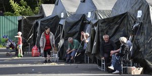 Άνθρωποι που απομακρύνθηκαν από μάχες μεταξύ ρωσικών και ουκρανικών δυνάμεων στην περιοχή του Κουρσκ κάθονται δίπλα σε σκηνές σε κέντρο προσωρινής διαμονής στο Κουρσκ της Ρωσίας