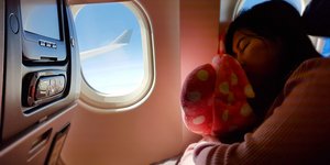 Γυναίκα ακουμπά το κεφάλι της στο παράθυρο αεροπλάνου