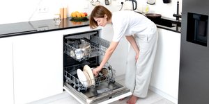 Γυναίκα βάζει πιάτα στο πλυντήριο πιάτων