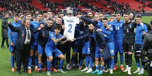 Οι ποδοσφαιριστές της εθνικής Ελλάδος κρατούν την μπλούζα του Τζορτζ Μπάλντοκ μπροστά από την κερκίδα των Ελλήνων φιλάθλων που βρέθηκαν στο Γουέμπλεϊ 