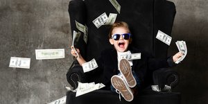 Αγοράκι κάθεται σε πολυθρόνα και πετά στον αέρα χαρτονομίσματα