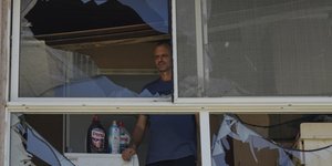 Κάτοικος βομβαρδισμένου σπιτιού κοιτάζει έξω από το παράθυρο