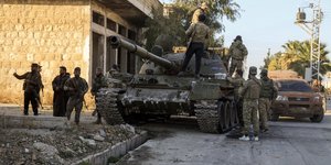 Μαχητές της συριακής αντιπολίτευσης στέκονται πάνω σε ένα καταληφθέν άρμα του συριακού στρατού στην πόλη Μααράτ αλ-Νουμάν, νοτιοδυτικά του Χαλεπίου