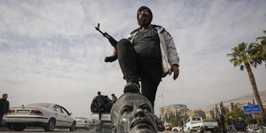 Ένας μαχητής της αντιπολίτευσης πατάει πάνω σε μια σπασμένη προτομή του αείμνηστου Σύρου προέδρου Χαφέζ Άσαντ στη Δαμασκό, Συρία, Κυριακή 8 Δεκεμβρίου 2024