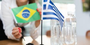 Γυναίκα τοποθετεί μια σημαία της Βραζιλίας σε ένα τραπέζι δίπλα από μία ελληνική