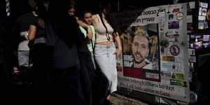 Άνθρωποι περπατούν δίπλα σε αφίσα του Ελκάνα Μποχμπότ ο οποίος απήχθη στο φεστιβάλ Nova από τη Χαμάς και δεν έχει απελευθερωθεί