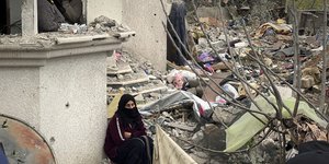 Γυναίκα κάθεται μπροστά σε ερείπια σπιτιού στη Γάζα
