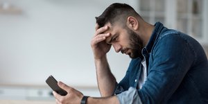 Άνδρας κοιτάζει το κινητό του τηλέφωνο