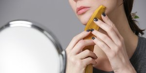 Γυναίκα τρίβει μπανανόφλουδα στο πρόσωπό της