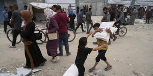 Παιδιά στη Γάζα κουβαλούν σακιά με αλεύρι, μέρος της ανθρωπιστικής βοήθειας του ΟΗΕ