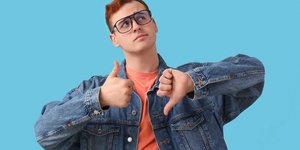 άνδρας με γυαλιά κάνει χειρονομία με τους αντίχειρες