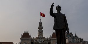 Βιετναμέζικη σημαία κυματίζει πάνω από το δημαρχείο, πίσω από το άγαλμα του Χο Τσι Μινχ στο Βιετνάμ