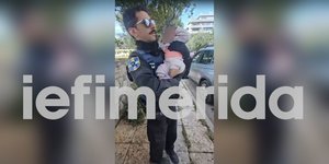 Αστυνομικός κρατάει το βρέφος στην αγκαλιά του