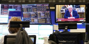 Εργαζόμενη στο χρηματιστήριο της Φρανκφούρτης παρακολουθεί τις τιμές των μετοχών και τον Ντόναλντ Τραμπ στην τηλεόραση