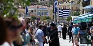 Το λιμάνι της Σύμης με κόσμο και φόντο την ελληνική σημαία