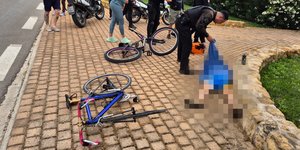 Ο ποδηλάτης στο έδαφος και αστυνομικοί του δίνουν τις πρώτες βοήθειες